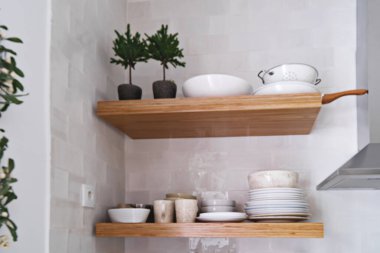 Blurred wooden kitchen shelves with tableware on white brick tile wall in Scandinavian style
