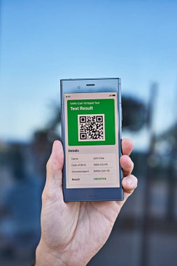 Male hand holds smartphone displaying an app negative test result of covid-19. Express PCR test, digital result on mobile application concept, closeup