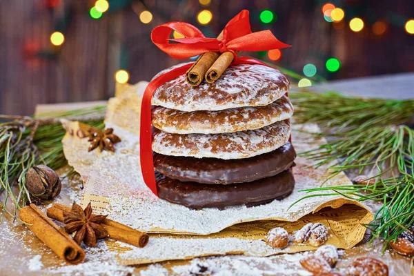 Stack of Christmas gingerbread rounds cookies tied with red ribbon icing sugar Xmas holiday table setting, decorated with garlands, nuts, and cinnamon sticks