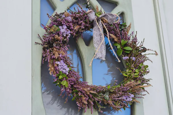 Wreath made from heather and other forest herbs with ribbon on door of house. Ancient Celtic tradition of celebrating the fall