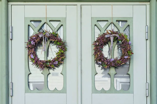 Wreath made from heather and other forest herbs with ribbon on door of house. Ancient Celtic tradition of celebrating the fall
