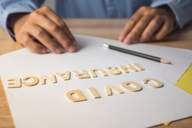 Covid sigortası için broker sunar. Belgelerde tahta yazılar var. Kopyalama alanı ile ortamı kapat.
