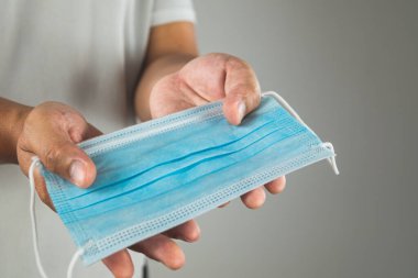 Tıbbi konsept. Hastalık koruması için birine mavi maske vermek. Grip, grip, Covid, toz pm2.5 gibi. Bu yakın çekim maske üzerine odaklanmış. Metin, resim veya illüstrasyon için alanı kopyala.