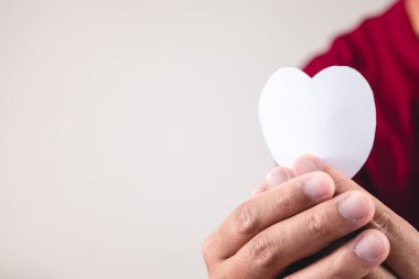 Adamın elinde beyaz kağıt bir kalp var. Kopyalama alanı ile yakın çekim.