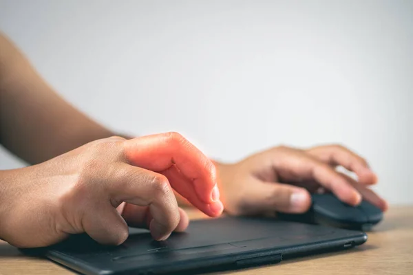 The man uses a mouse and drawing pad until his fingers pain. Office syndrome concept. Pain symptom area is shown with red color. Medium close up shot with copy space.