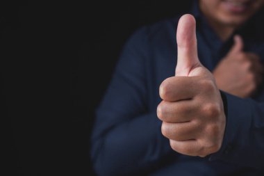 Person that wear dark blue shirt shows thumbs up sign. Salaryman or business man. Like or good concept. Close up shot with copy space.