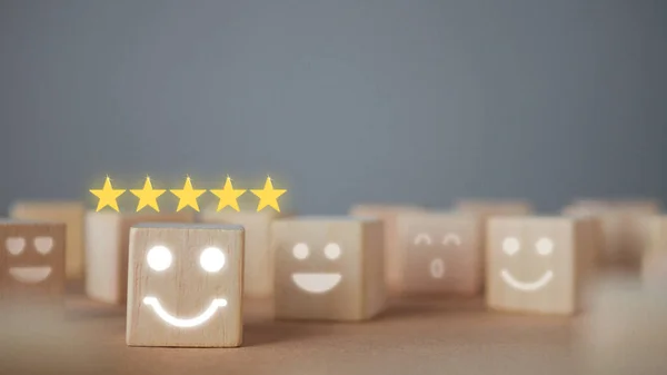 Evaluation and satisfaction concept. Five stars and smile emojis show an excellent job. Close up shot on wood block with copy space. There some noise and gain.