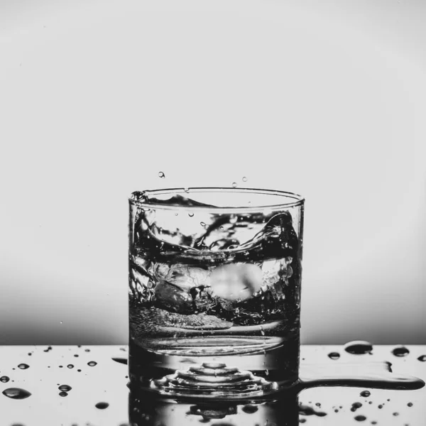 新鲜的冰块掉到玻璃杯中，与水隔绝 — 图库照片