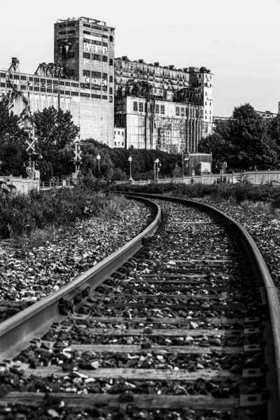 An abandoned rail tracks and a functional railroad in Montreal with rusty rails and grey gravel.
