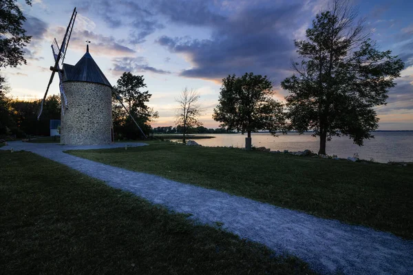 Old stone windmill with four blades. Stylized tower under the old mill against the blue sky. Canada