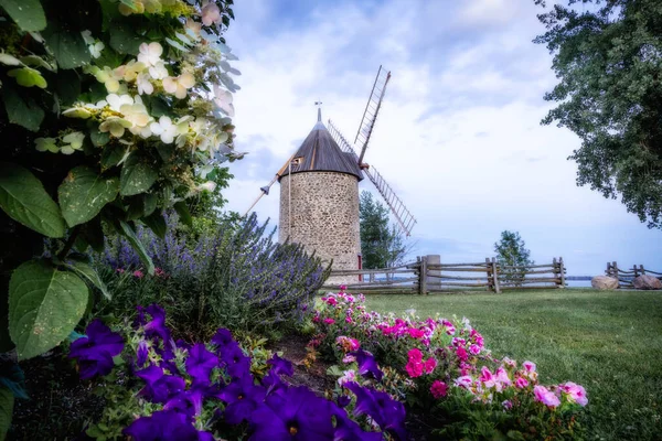 Old stone windmill with four blades. Stylized tower under the old mill against the blue sky. Canada