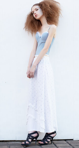 Молодая стройная красавица кудрявая рыжая женщина позирует в студии
