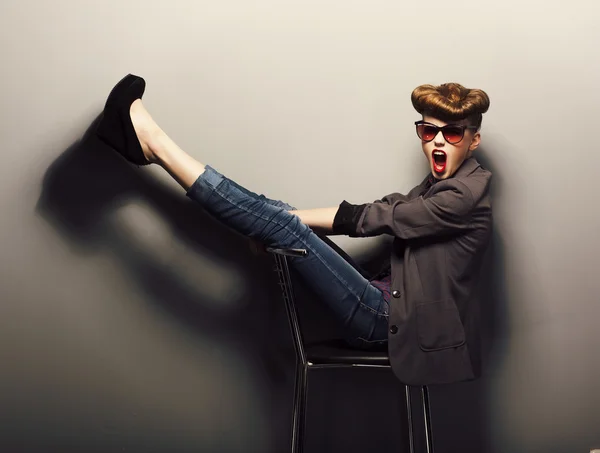 Funny girl sitting in sunglasses on chair in studio - vintage style — Stock Photo, Image