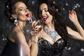 glücklich lachende Frauen, die Champagner trinken und Weihnachtslieder singen