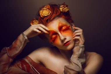 BodyArt. hayal gücü. Kırmızı - altın makyaj ve çiçekler ile sanatsal bir kadın. Boyama