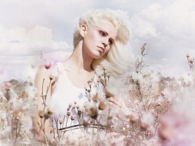Blossom. Beauty Blonde in Windy Field with Flowers. Nature. Springtime