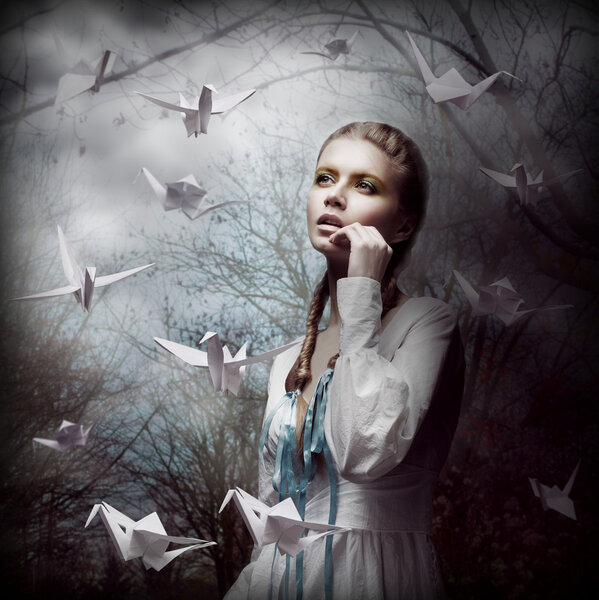 Inspiration. Woman with Flying White Origami Swans in Dark Mystic Forest