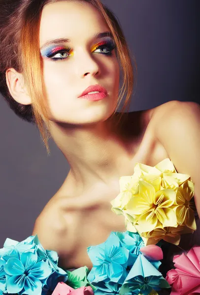 Porträt einer jungen Schönheit mit bunten Origami-Blumen. helles Augen-Make-up — Stockfoto