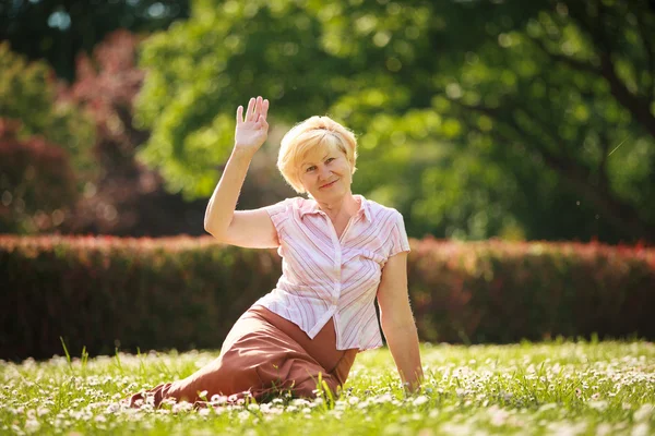 Maturità. Europeo bianco capelli donna seduta su erba e divertirsi — Foto Stock