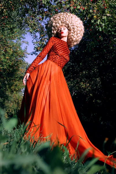 Fantasía. Mujer estilizada artística en vestido rojo de moda y gran peluca rizada —  Fotos de Stock