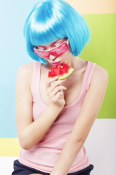 Mulher na moda em azul Wig e ping óculos comendo melancia — Fotografia de Stock