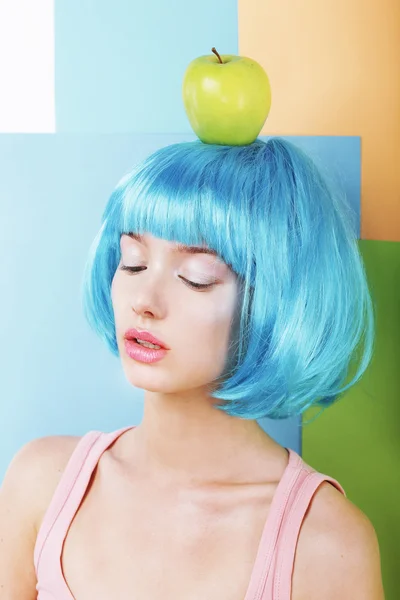 Mulher estilizada bizarro em azul Wig com maçã verde — Fotografia de Stock