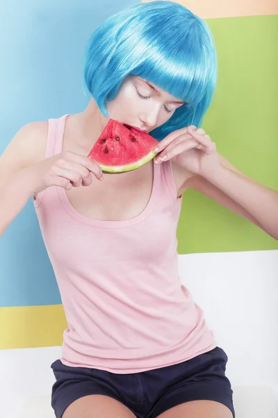 Schöne verträumte Frau mit blauer Perücke, die eine Scheibe Wassermelone hält — Stockfoto