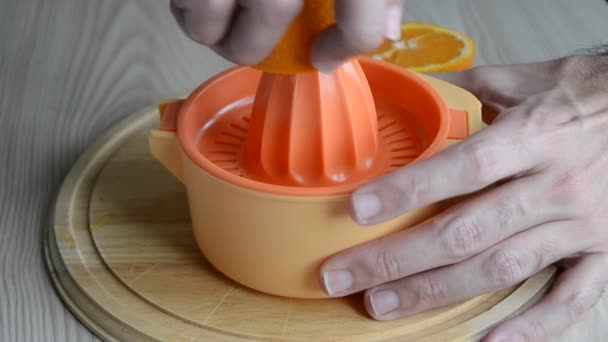 Um homem a apertar uma laranja na mesa — Vídeo de Stock