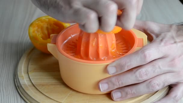 Um homem a apertar uma laranja na mesa — Vídeo de Stock