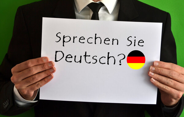 Бизнесмен показывает лист с текстом Sprechen Sie Deutsch
