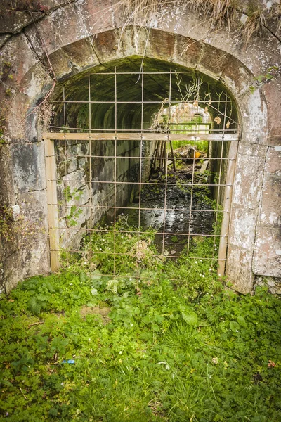 Culvert arqueado velho em uma parede de pedra velha — Fotografia de Stock