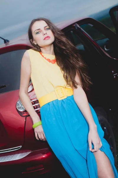 Giovane donna bruna in piedi vicino auto rossa — Foto Stock