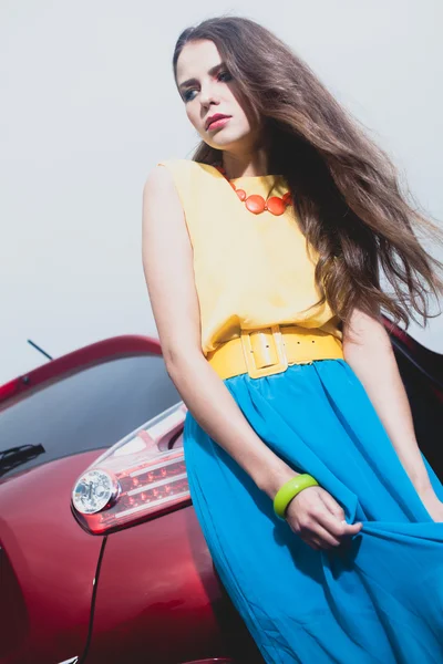 Giovane donna bruna in piedi vicino auto rossa — Foto Stock