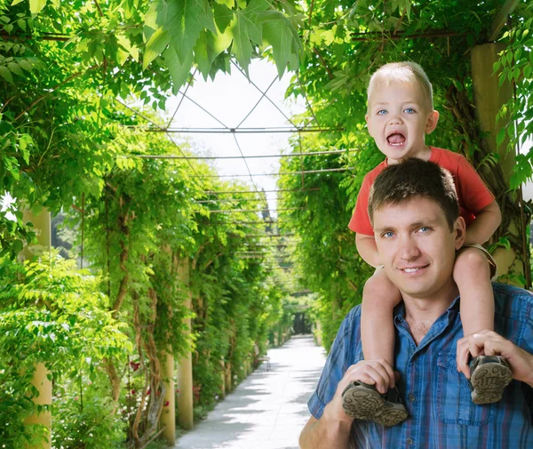 Boy sits on shoulder beside father — Stock Photo, Image