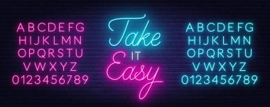 Take it Easy neon quote on a brick wall.