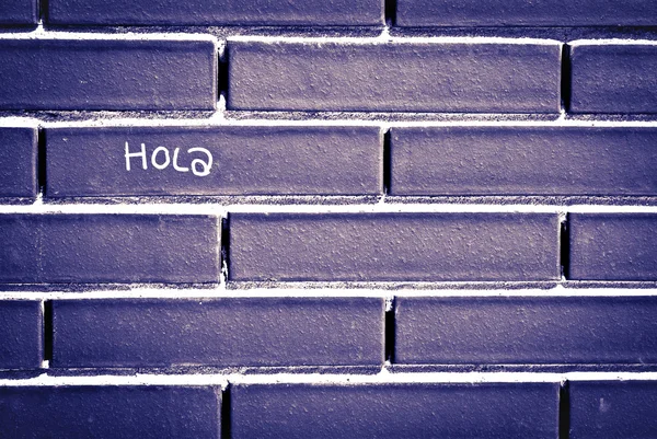 Spaans Hallo 'hola' geschreven over bakstenen muur — Stockfoto