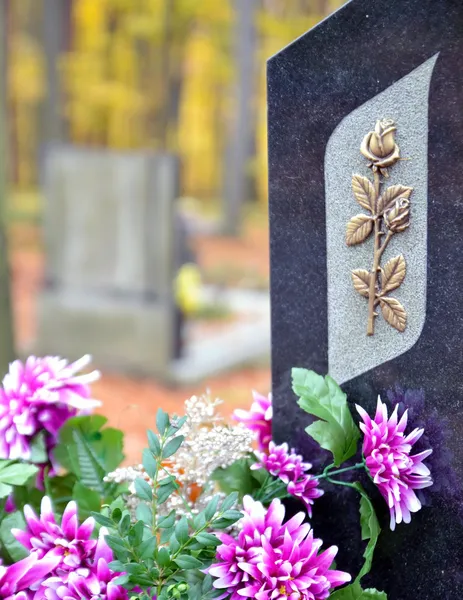Grafsteen met Gouden Roos en paarse bloemen — Stockfoto