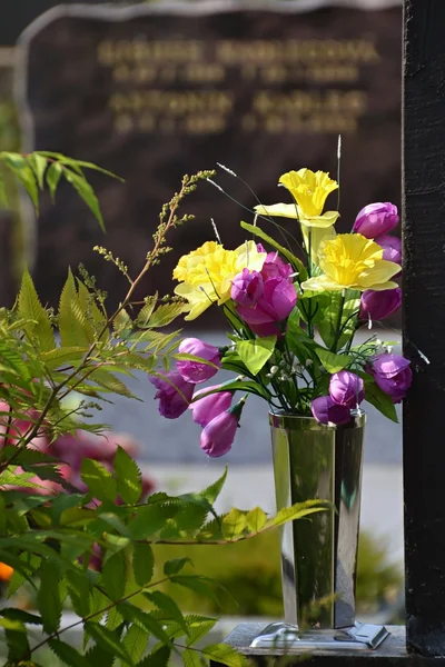 Kleurrijke bloemen in een vaas op een graf — Stockfoto