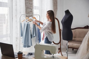 Malzeme seçiyorum. Kadın moda tasarımcısı atölyedeki yeni kıyafetler üzerinde çalışıyor..