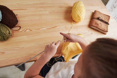 Manzarayı kapat. Çocuk evde örgü örüyor. Tahta masanın yanında oturan tatlı küçük kız yeni şeyler öğreniyor..