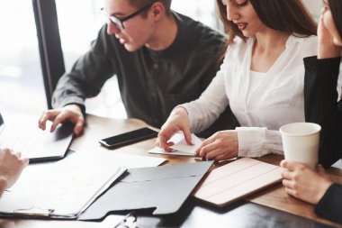 Adam dizüstü bilgisayar kullanıyor. Pencerenin yanındaki odada oturan genç öğrenciler proje üzerinde çalışıyorlar..