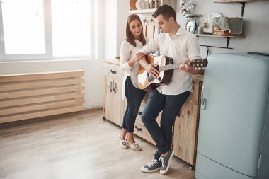 Temiz bir uzay odasında. Genç gitarist mutfakta kız arkadaşına aşk şarkısı çalıyor..