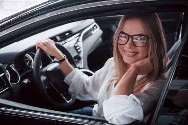 Kadın bu aracı satın alacak. Yeni arabasında oturan güzel sarışın kız..