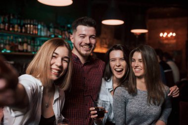 Telefondaki fotoğrafın kopyası. Arkadaşlar güzel bir gece kulübünde selfie çekiyorlar. İçkiler ellerde.