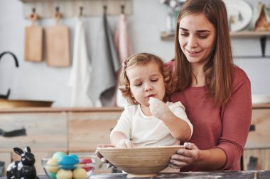 Hayır, henüz yiyemezsin. Anne, kızına Paskalya tatili için yumurta boyamayı öğretiyor..