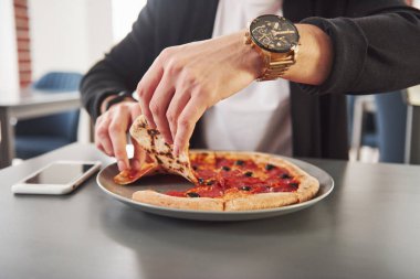 Bir dilim alıyorum. Sosis halkalı ve zeytinli lezzetli bir pizza resmi..