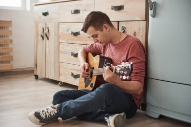 Müzisyen hafta sonu evde, mutfakta akustik gitar çalar..