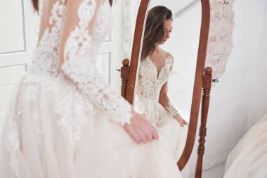 Gelinin aynadaki yansıması. Elbiseyi el yapımı kıyafetler stüdyosuna sığdırma süreci..