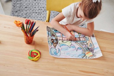 İşlem halinde. Sanat okulundaki tatlı küçük kız ilk resimlerini kalem ve kalemle çiziyor..