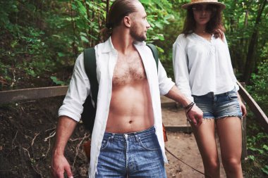 Sırt çantalı iki doğa yürüyüşçüsü. Bir yaz günü yürürken el ele tutuşan erkek ve kadın..